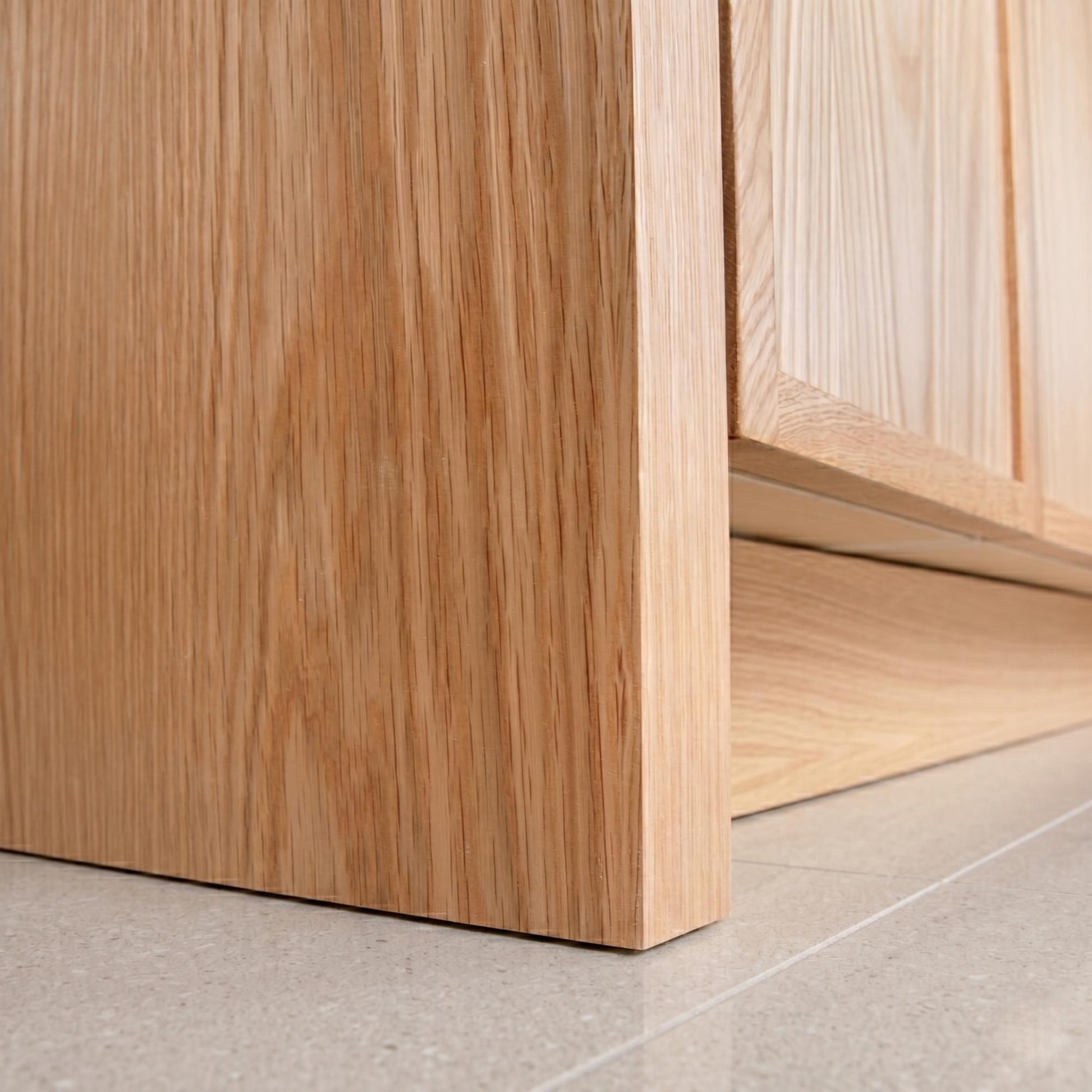 Close-up of a wooden cabinet corner on a light gray floor.