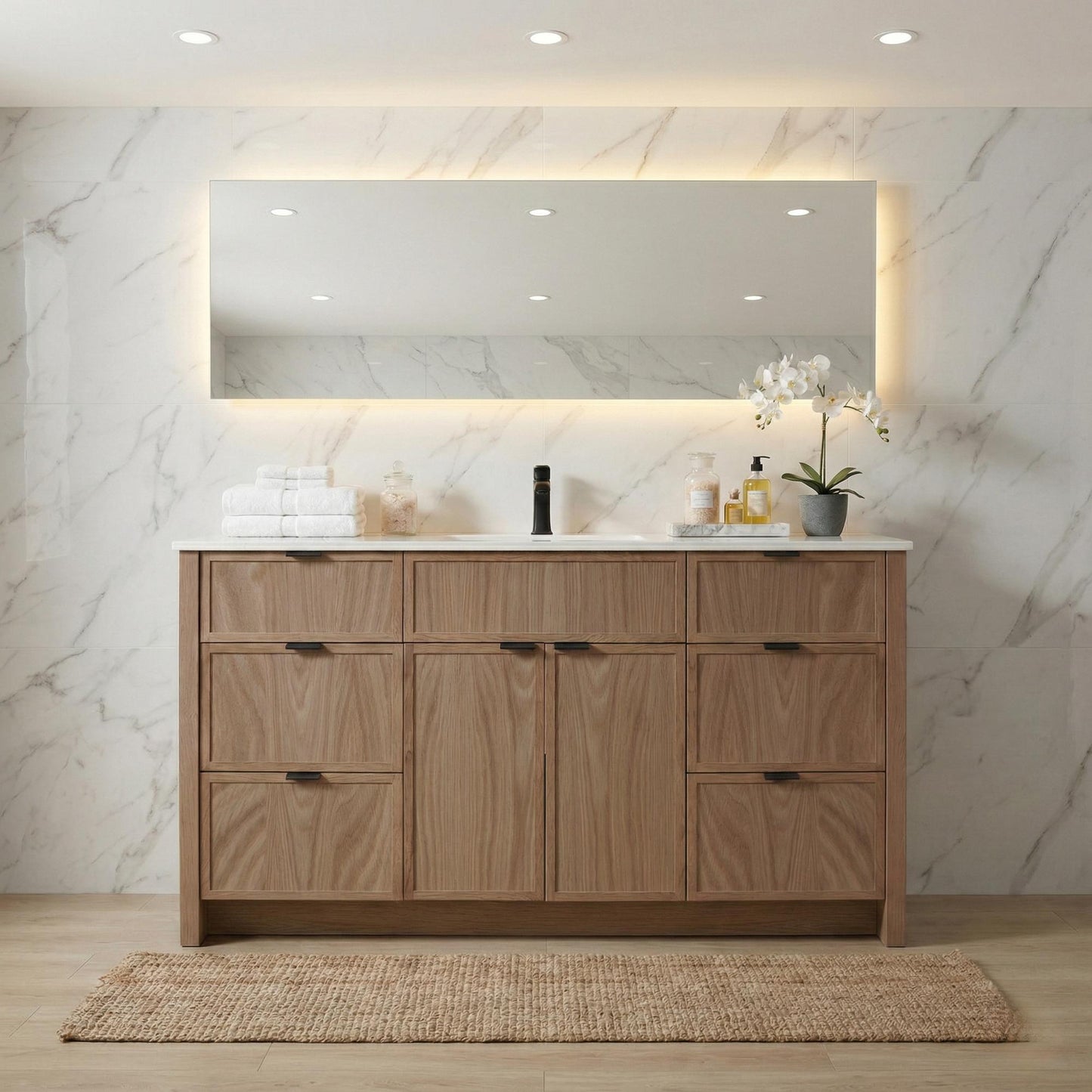 Bathroom vanity with wooden cabinets, mirror, and decorative items against a marble wall.