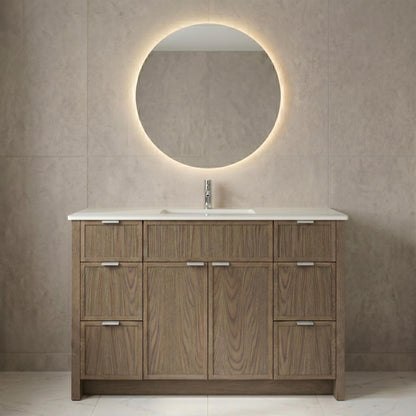 Wooden bathroom vanity with round mirror and light fixture on a tiled wall.