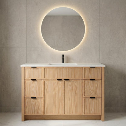 Bathroom vanity with wooden cabinets, round mirror, and white countertop against a beige tiled wall.